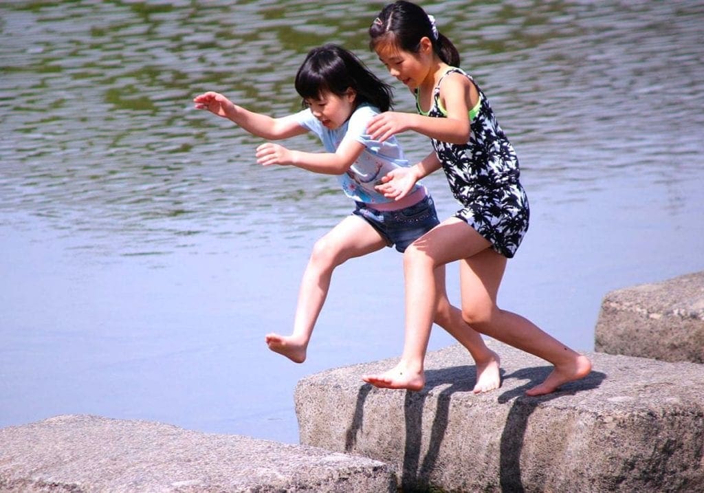 Små piger, som springer rundt på stenene i Kyoto
