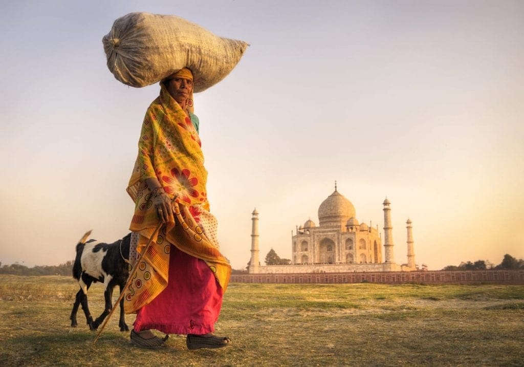 En kvinde med hendes ged foran Taj Mahal