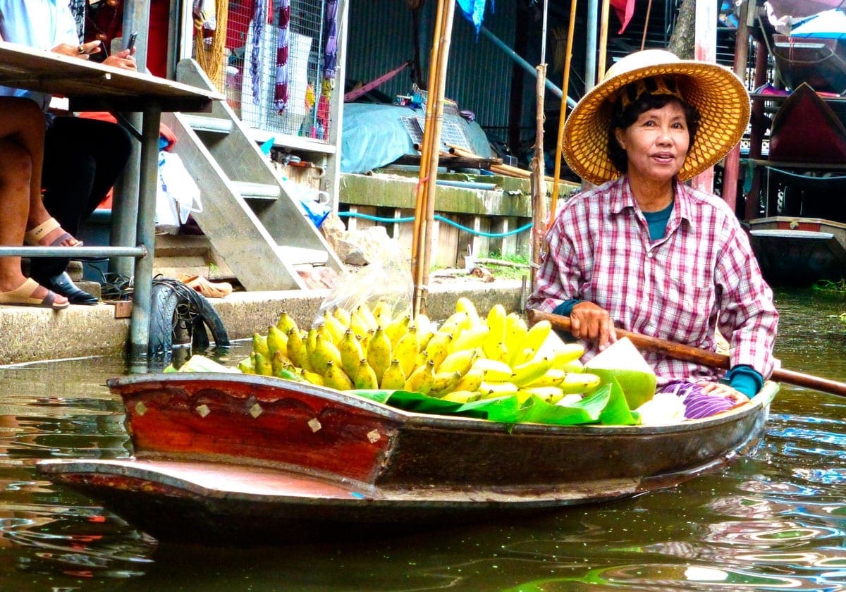 Kvinde med frugtbåd på floden i Bangkok